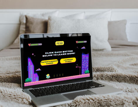 An open laptop on a bed with a screen displaying the text "Click Each Button to Learn More!"